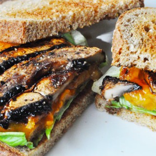 Portobello Mushroom Bacon BLT sandwich with the toast half on, on one half of the sandwich on a white plate