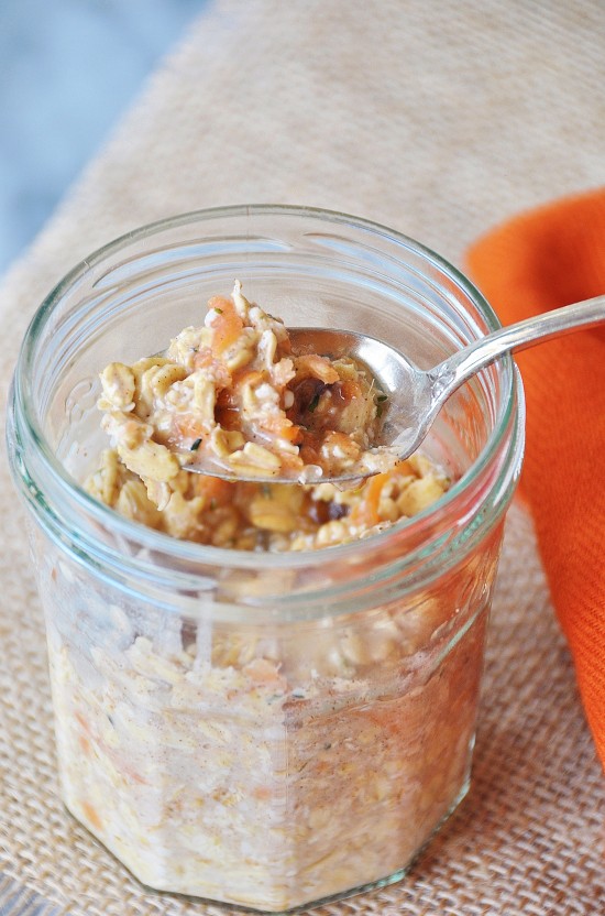 Vegan Carrot Cake Overnight Oats in a clear mason jar with a silver spoon in it and an orange napkin next to it