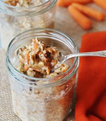 Vegan Carrot Cake Overnight Oats in a glass mason jar with a silver spoon in it and an orange napkin and carrots next to the jar