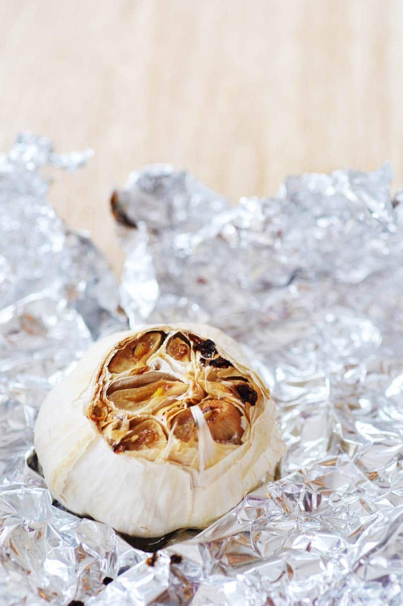 A head of roasted garlic on a piece of foil.