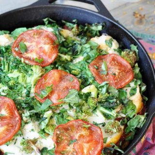 Vegan Deep Dish Pizza in an iron skillet with a red napkin next tothe pan and a white dish of red crushed peppers
