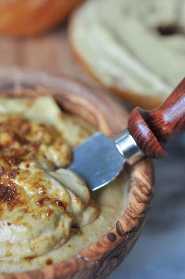 A close up photo of vegan pumpkin spread with coconut sugar sprinkled on top in a wood bowl with a wood handle.