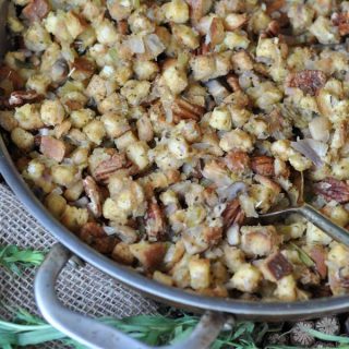 Vegan stuffing in a copper pan with fresh herbs next to the pan