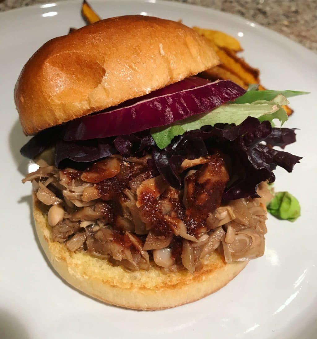 A vegan pulled pork BBQ sandwich on a white plate