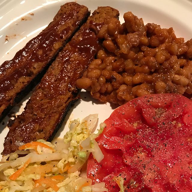 A plate of vegan brisket, baked beans Carolina slaw and tomato