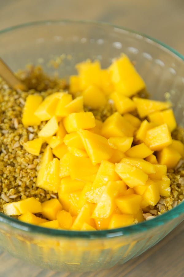A glass bowl with curried quinoa and mango