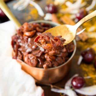 Cherry Onion confit on a gold spoon in front of a copper pot