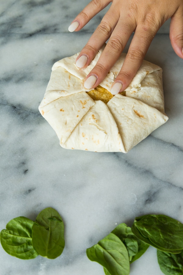 A perfectly folded crunchwrap supreme on a marble surface