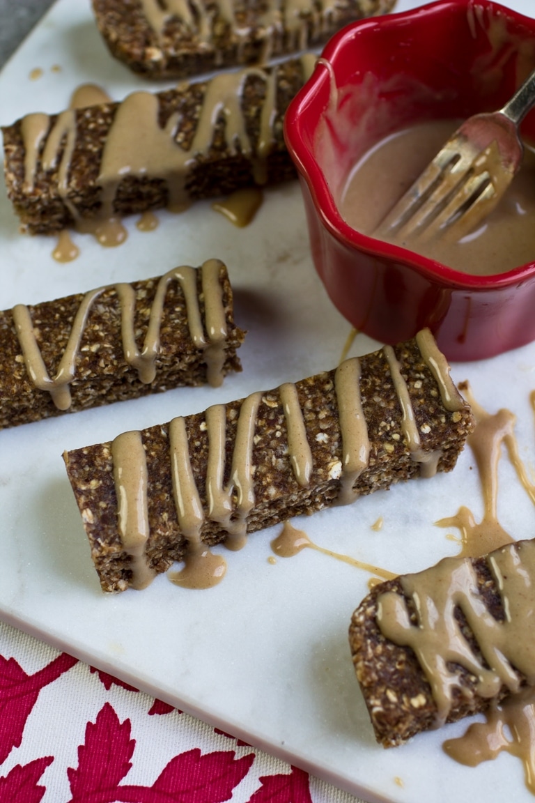 No-bake cinnamon bars on a white plate with a red bowl of icing
