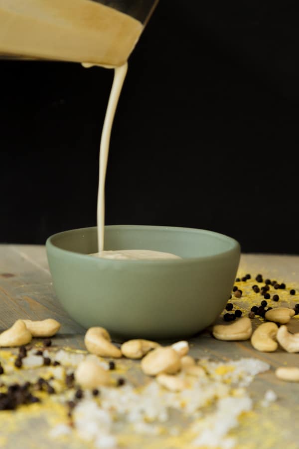 Cesar dressing being poured into a bowl with ingredients in front of it