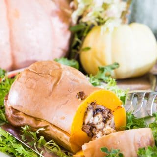 Stuffed butternut squash filled with stuffing on a bed of greens on a thanksgiving table