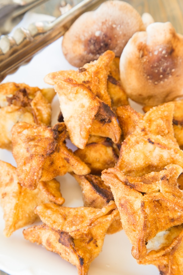 Fried ricotta and shiitake stuffed wontons on a paper towel with tongs