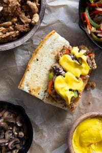 Building a philly cheesesteak end product with vegan cheese sauce, bell peppers, onions, mushrooms, and soy curls