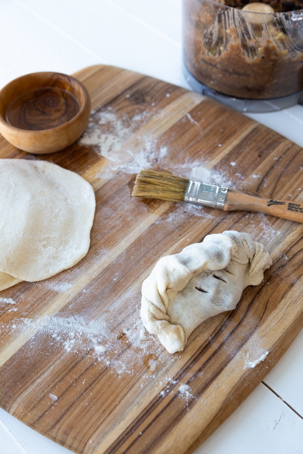 an uncooked empanada on a board before being baked