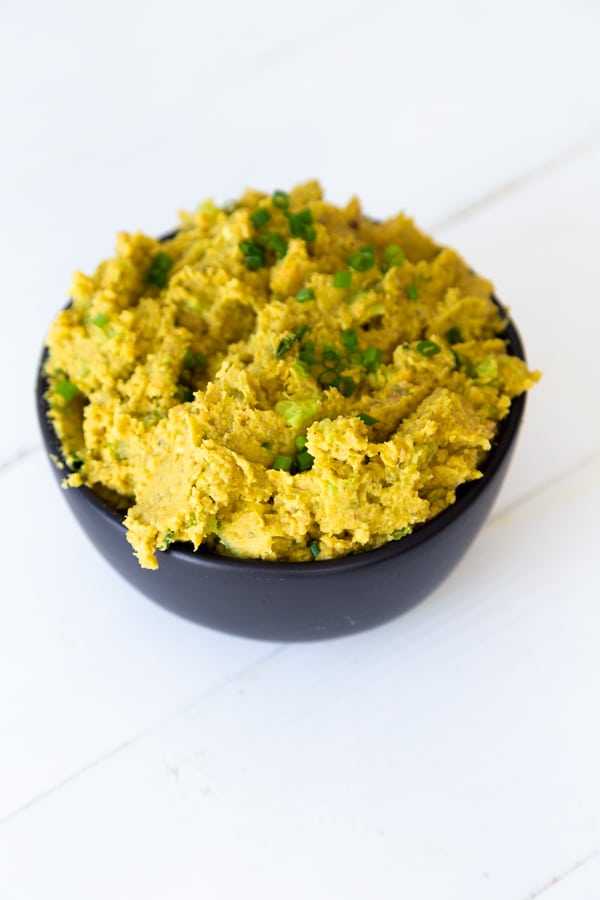 Chickpea salad in a black bowl on a white board.