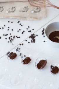an Easter egg candy mold with a bowl of melted chocolate and chocolate chips