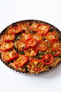 A cooked tomato and spinach tart in a tart pan