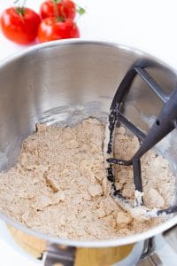 Flour and butter that looks like course meal in a silver mixing bowl