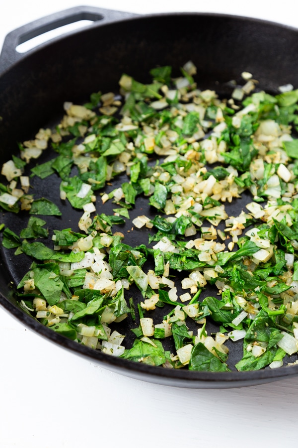 Onions and spinach cooked in a cast-iron skillet