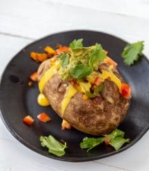 Process shot of a stuffed baked potato on a black plate.