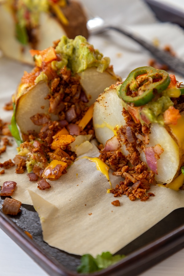 A stuffed potato cut in half with the fillings dripping down the sides. 