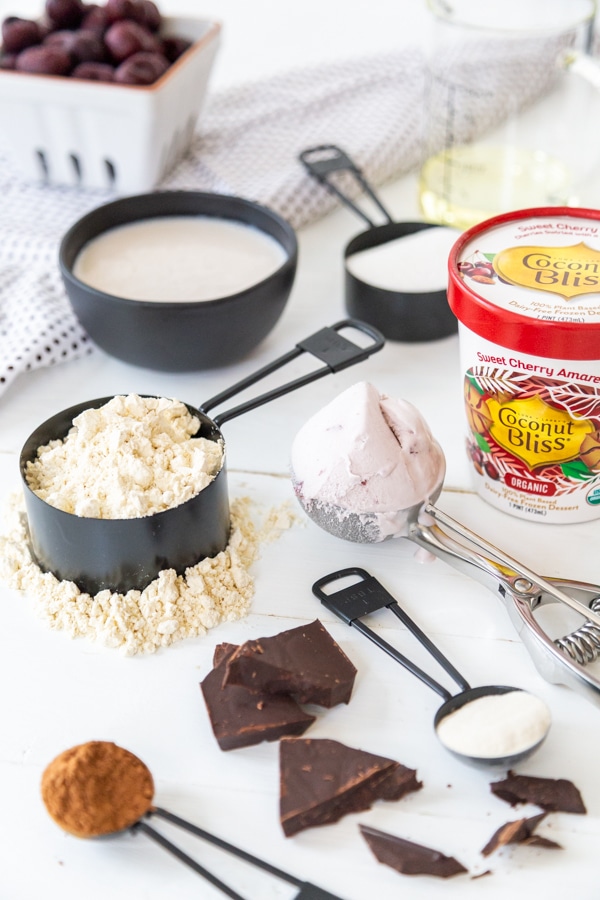 The ingredients for a chocolate cherry ice cream cake on a white board.