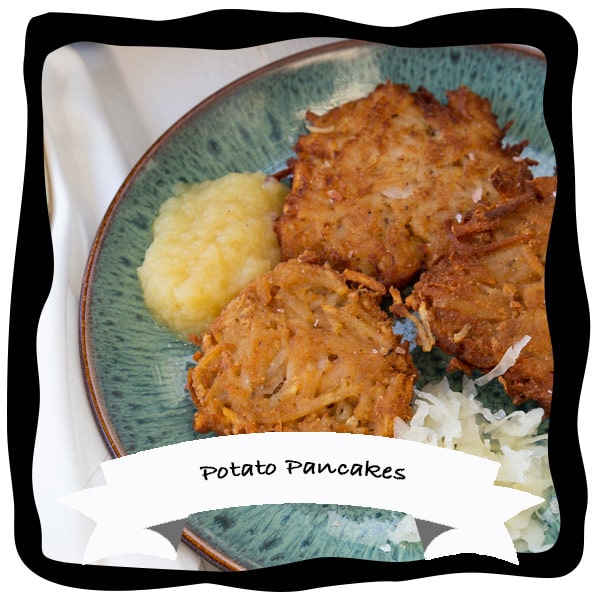 potato pancakes on a green plate with apple sauce and sour kraut