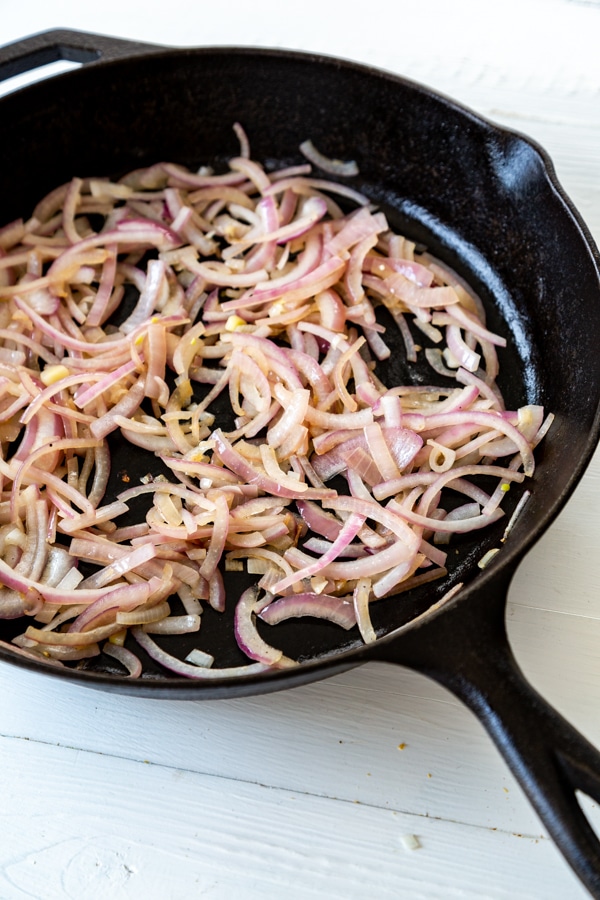 An iron skillet with slivers of onion.