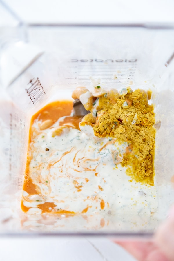 A blender with cashews, buffalo sauce, ranch dressing and other ingredients.