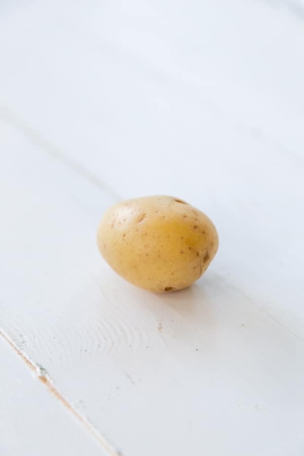 A small potato on a white wood table. 