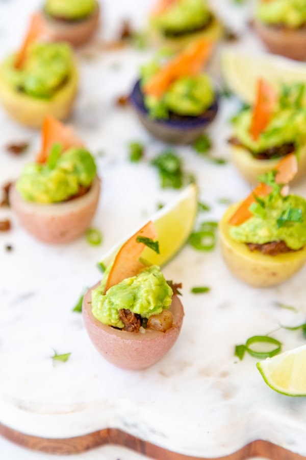 A marble and wood board filled with potato cup tacos.