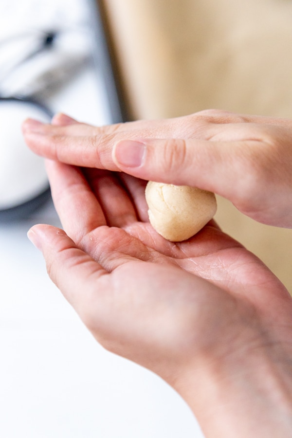 Two hands rolling cookie dough into a ball.