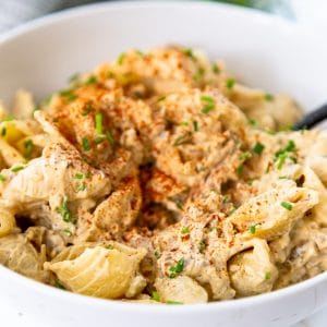 A white bowl with buffalo chicken mac and cheese with a fork in the bowl.