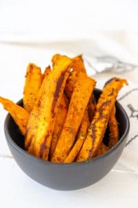 A black bowl filled with sweet potato fries.