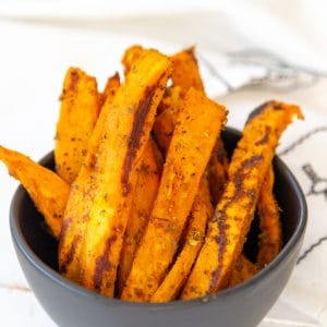 A black bowl filled with sweet potato fries.