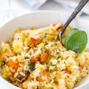 Squash risotto in a white bowl with a silver fork in the bowl.