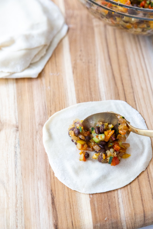 A round egg roll wrapper with vegetable filling in the center. 