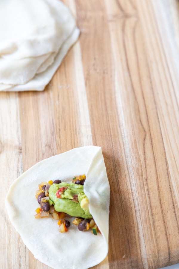 An egg roll wrapper with one side folded over the veggie filling. 