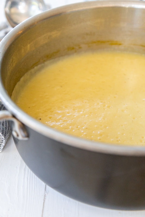 A pot of potato soup on a white wood table.