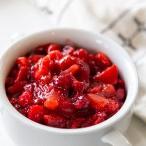 A white bowl with cranberry apple sauce next to a black and white napkin.
