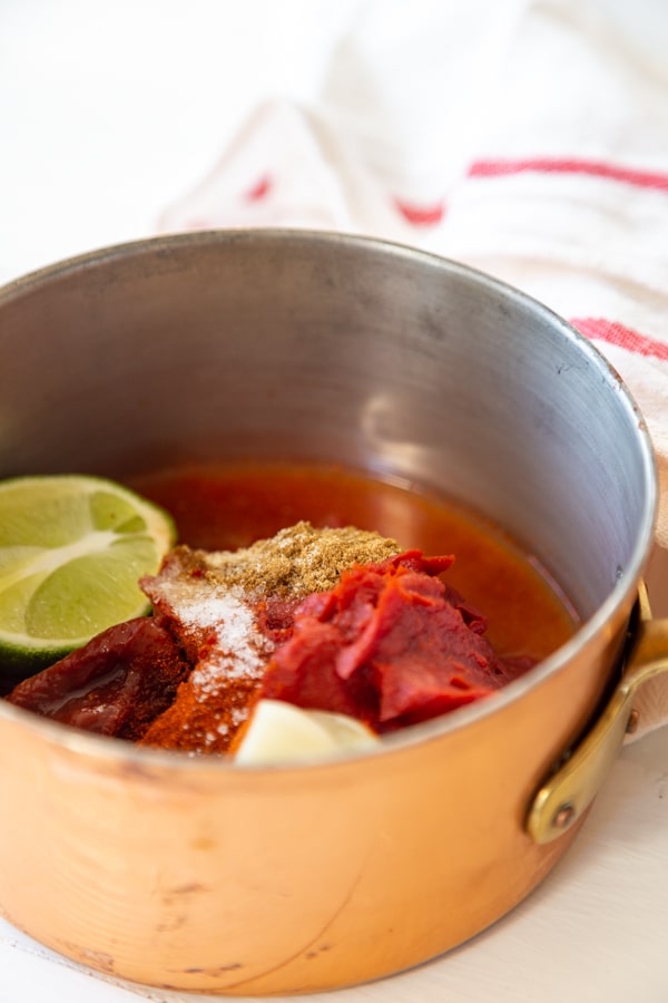 A copper pot with ingredients for bbq sauce.
