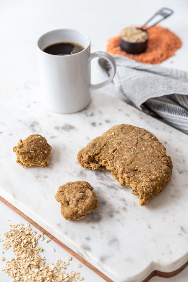 Seitan dough with 2 small pieces torn from the center on a marble board.