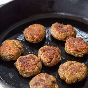 An iron skillet with breakfast sausage patties.