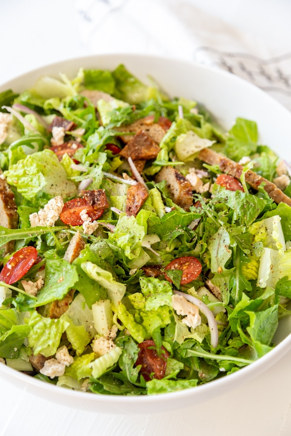 A tossed Cobb salad in a large white bowl.
