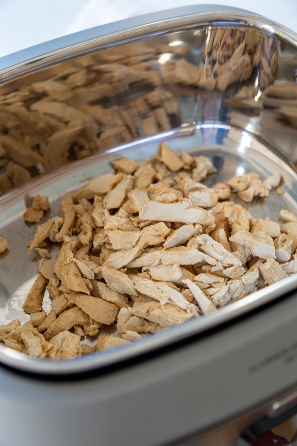 A slow cooker with pulled chicken.