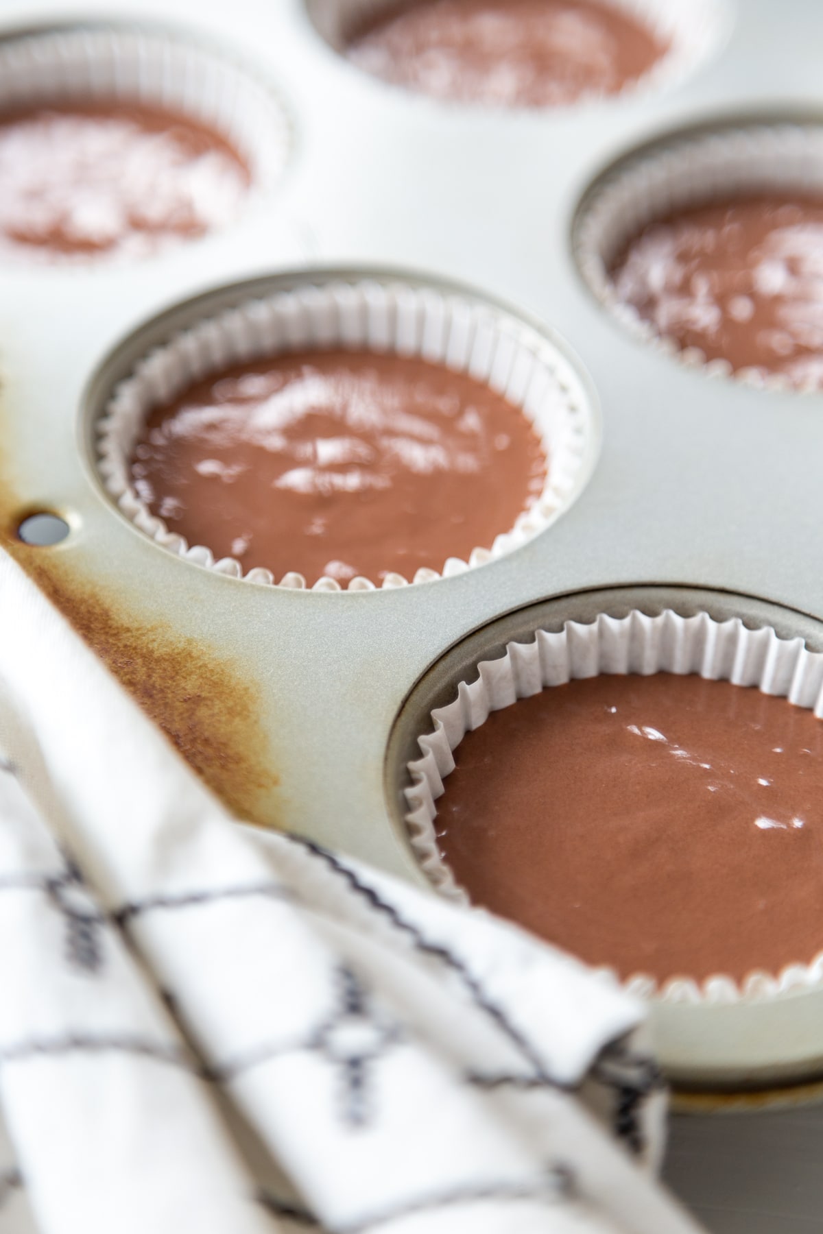 A muffin tin filled with unbaked chocolate cupcakes.
