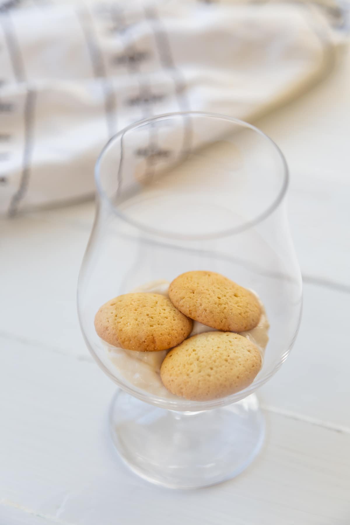 A glass with 3 vanilla wafers on the bottom.