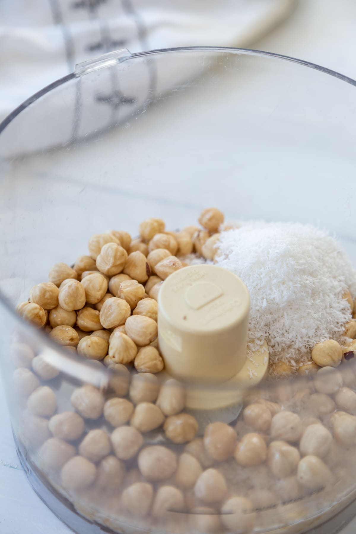A food processor with hazelnuts and dried coconut.