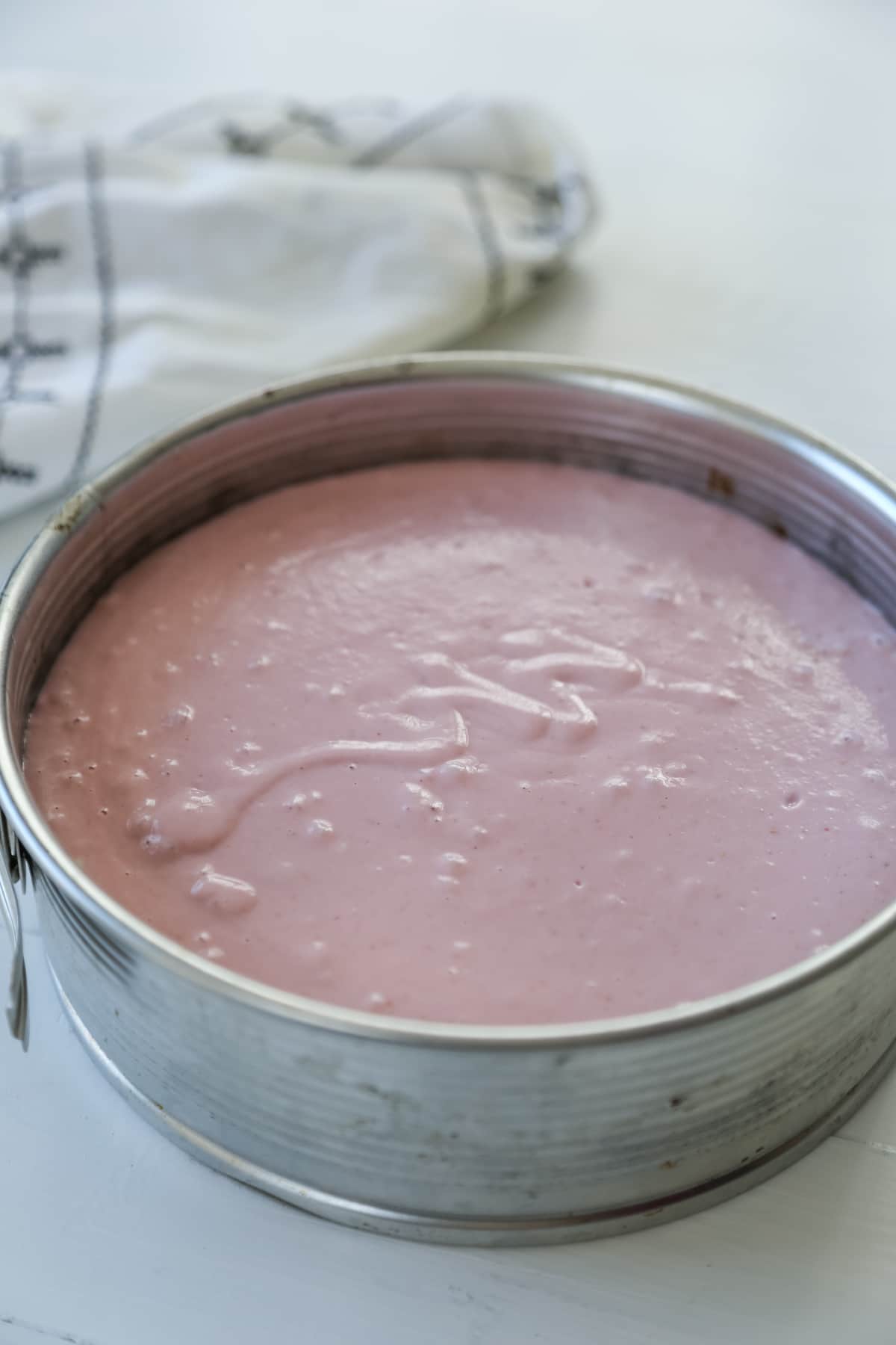Raspberry cheesecake in a silver springform pan.