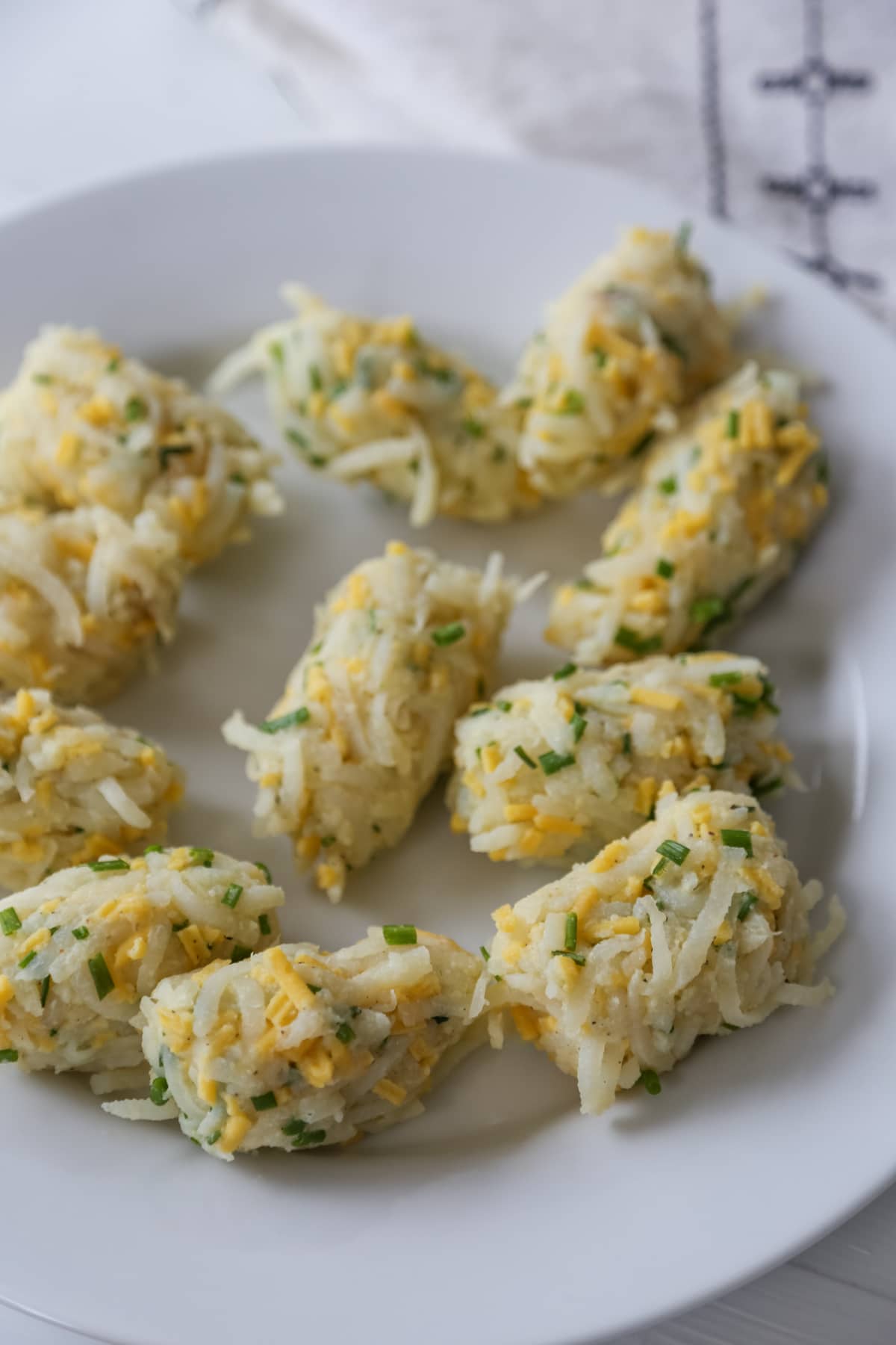 A white plate with uncooked tater tots.